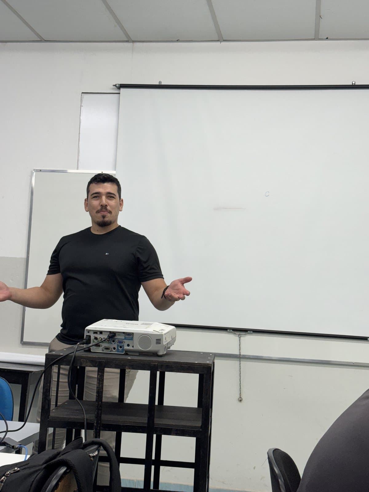 João Camilo teaching in a classroom, next to the projector